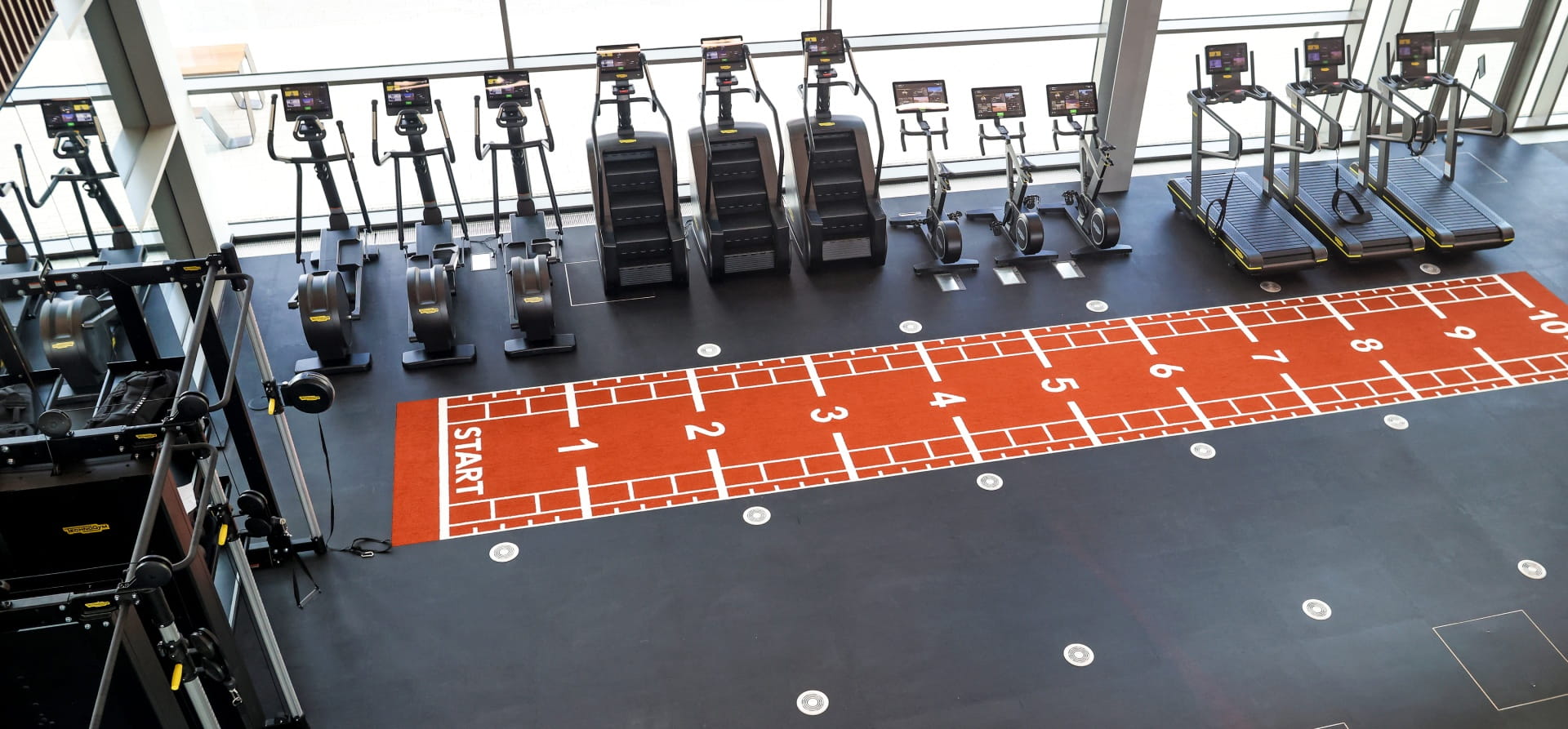 Black gym with red floor equipment and weights