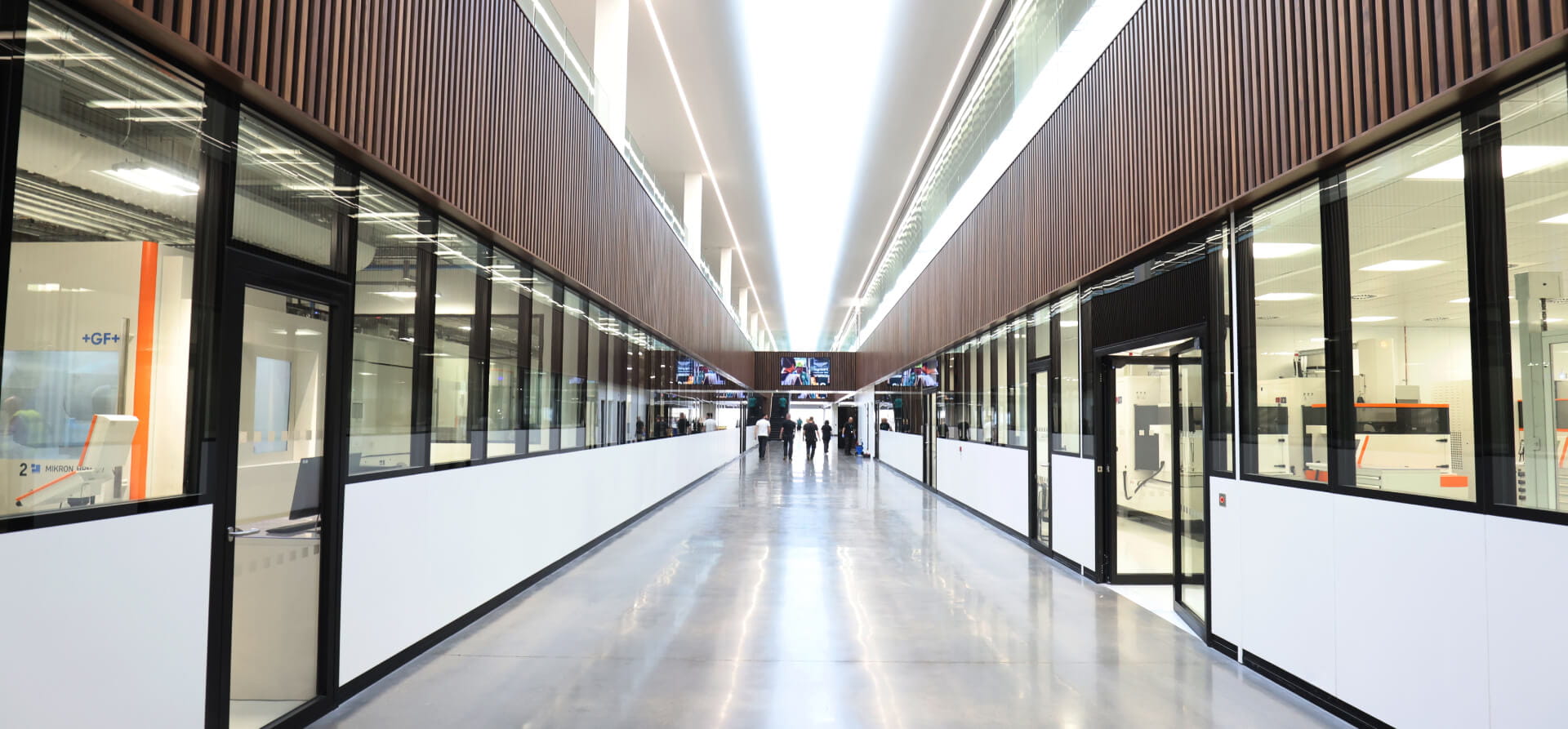 Grey floored corridor with offices on either side and a skylight lighting it