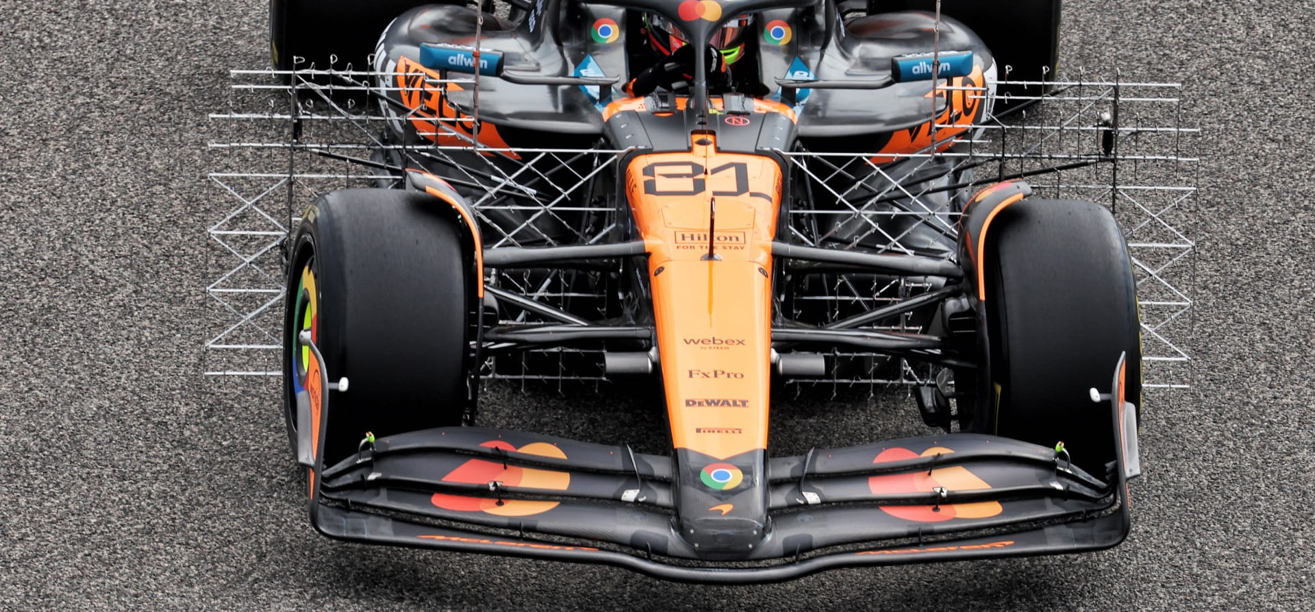 2025 McLaren f1 car with aero rakes protruding from its front behind the rear tyres