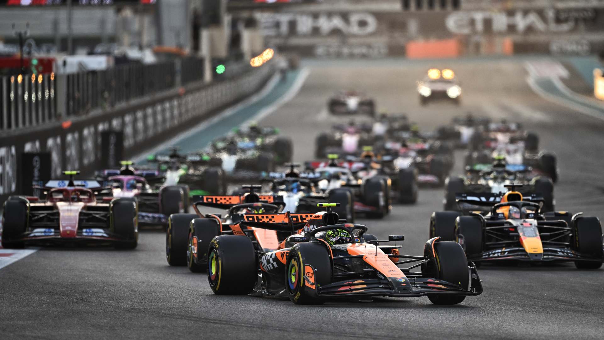 Orange McLaren leading a field of F1 cars away at the final grand prix of 2024 